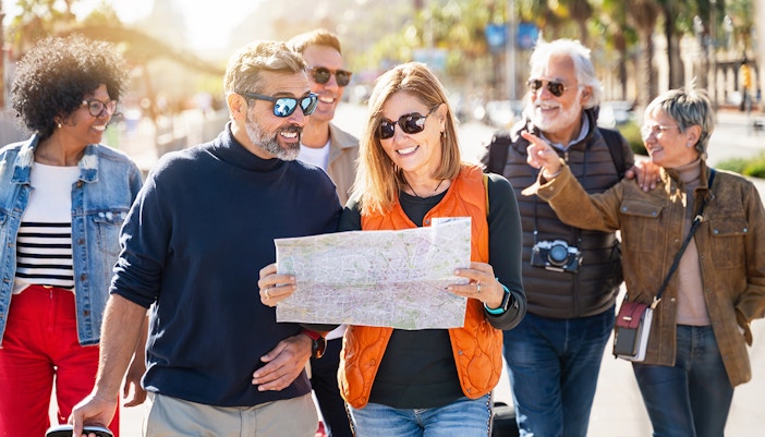 Friends exploring Rome with a map, walking on a sunny street.
