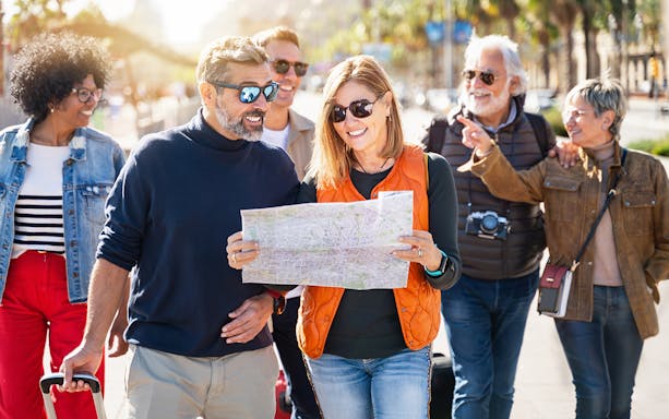 Friends exploring Rome with a map, walking on a sunny street.