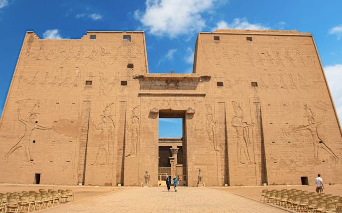 Visitors entering the Temple of Horus at Edfu, Egypt, with ancient carvings on the facade.