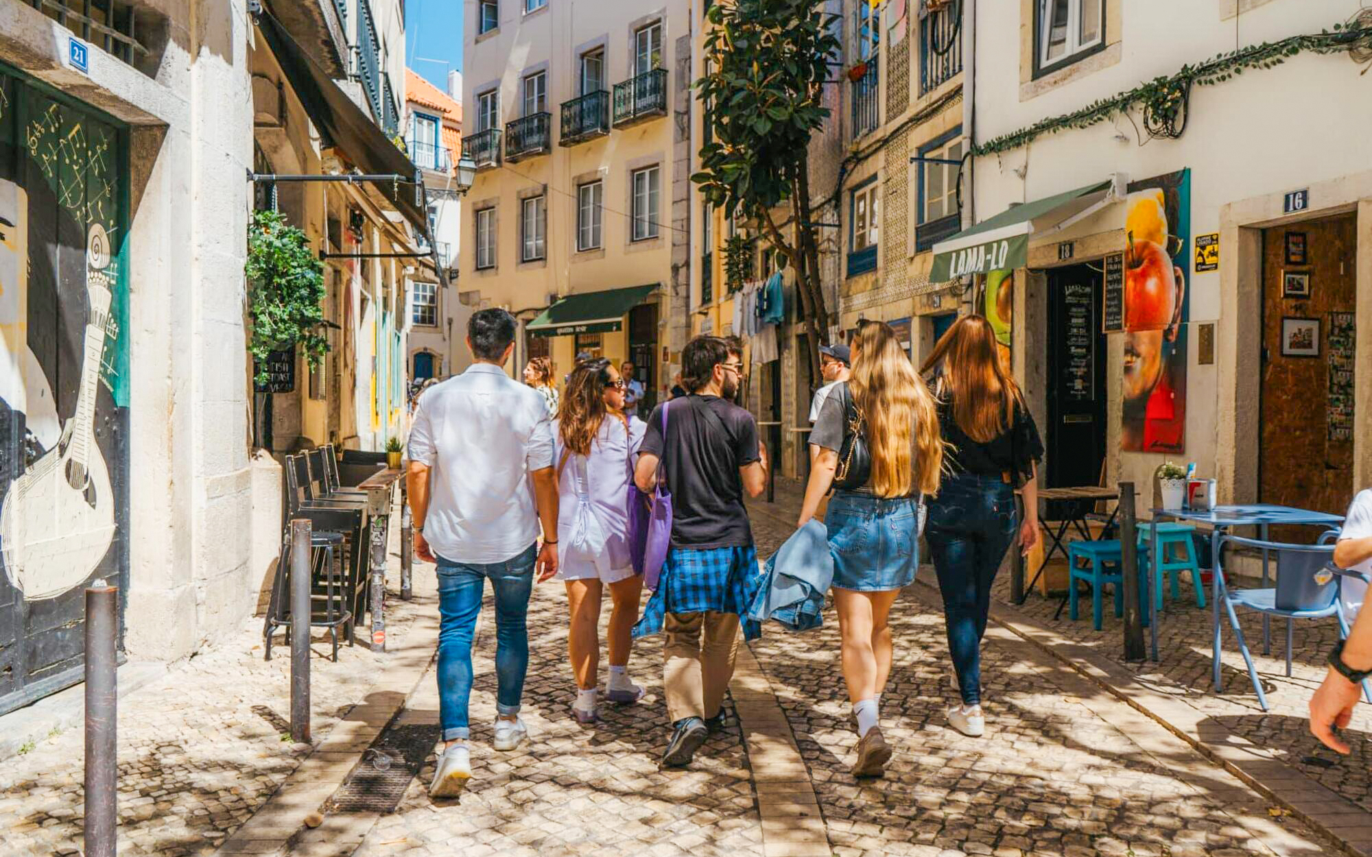 Tourists walking through Lisbon's historic streets, sampling local cuisine on a guided food tour.
