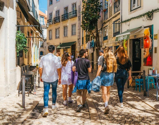 Tourists walking through a narrow street in Lisbon during a food tour.