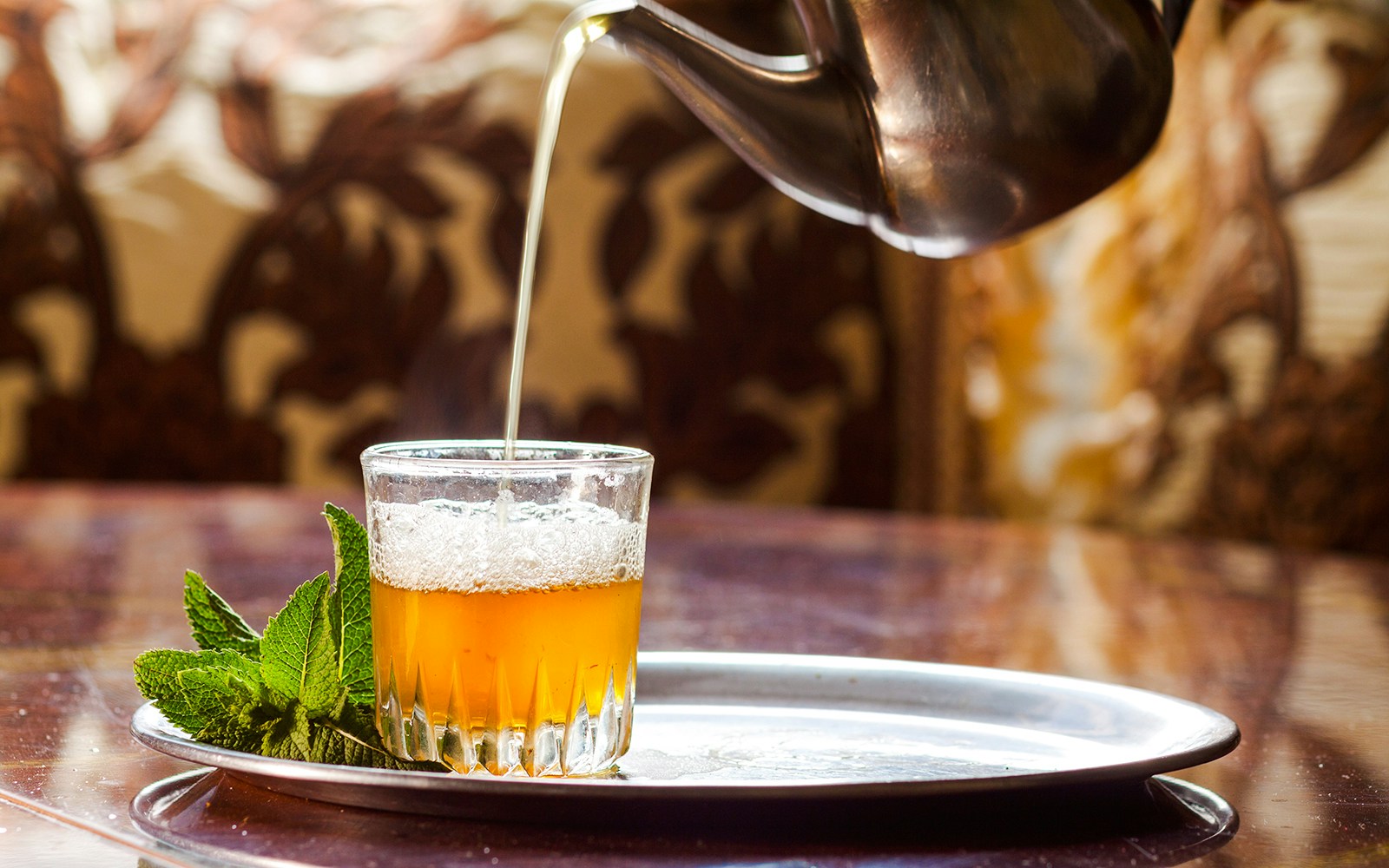 Moroccan mint tea being poured into a glass at Café Bousafsaf, Marrakech.