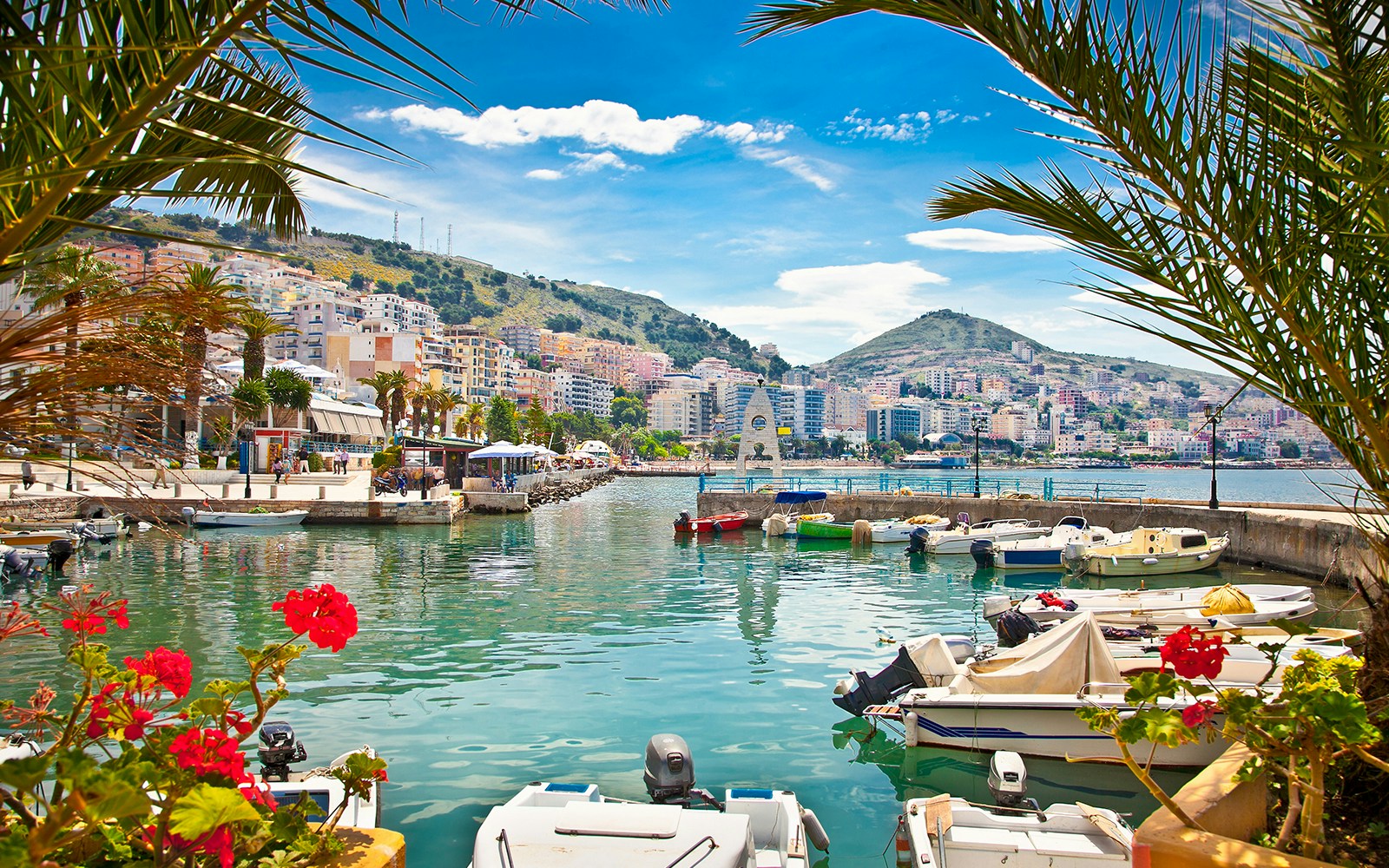 Saranda city waterfront with boats and hillside buildings, Albania.