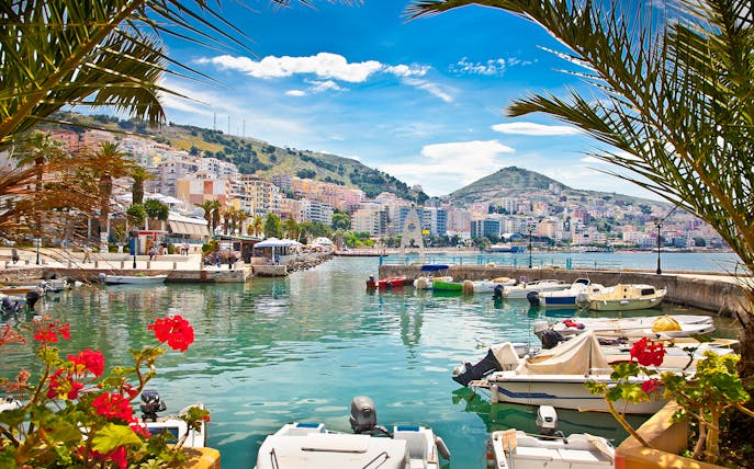Saranda city waterfront with boats and hillside buildings, Albania.