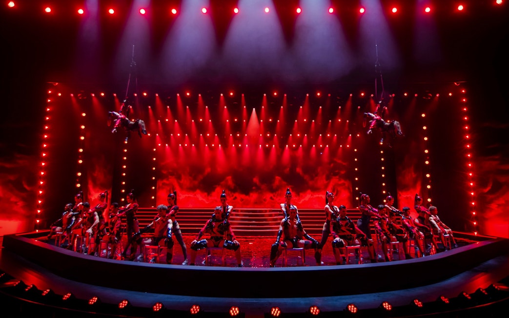 Performers on stage at Friedrichstadt Palast with dramatic red lighting.