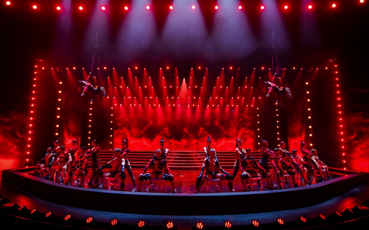 Performers on stage at Friedrichstadt Palast with dramatic red lighting.