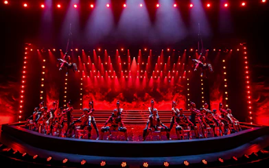 Performers on stage at Friedrichstadt Palast with dramatic red lighting.