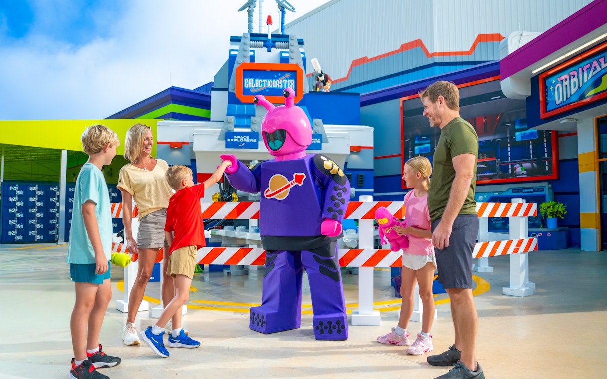Family interacting with a purple alien character at LEGOLAND California Resort's Galacticoaster.