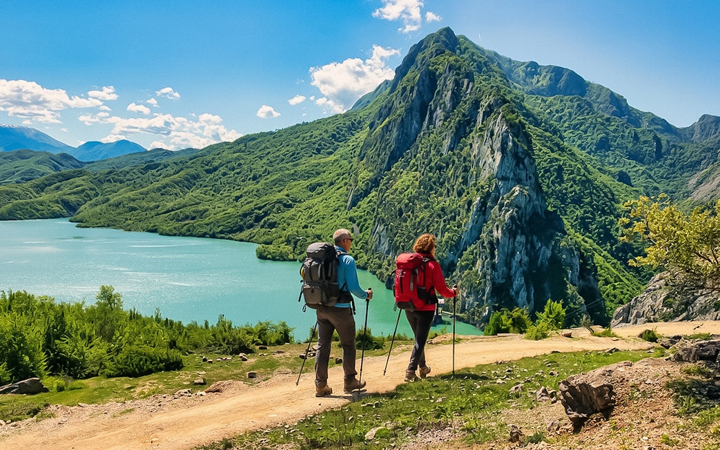 Guests hiking near Bovilla Lake with Gamti Mountains in the background.