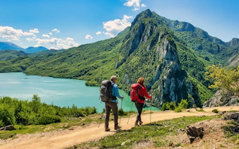Guests hiking near Bovilla Lake with Gamti Mountains in the background.