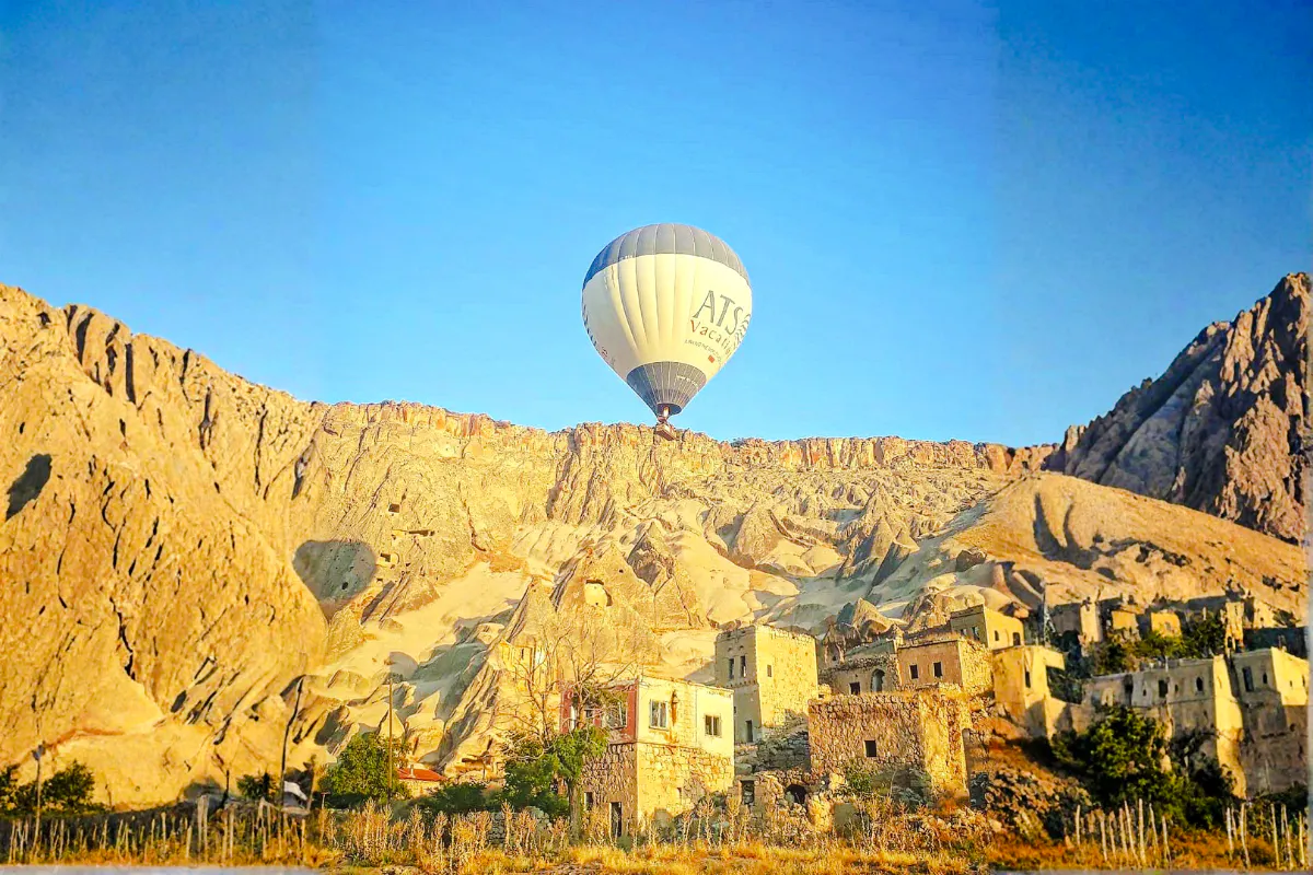 Hot air balloon over Ihlara Canyon at sunrise, Cappadocia, with rock formations and ancient dwellings.