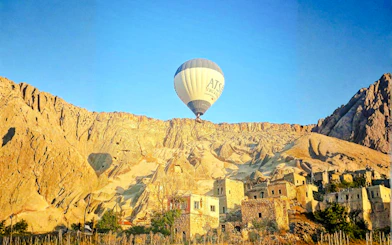 Hot air balloon over Ihlara Canyon at sunrise, Cappadocia, with rock formations and ancient dwellings.
