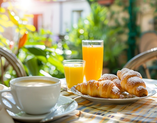 Croissants and orange juice on a sunny outdoor café table.