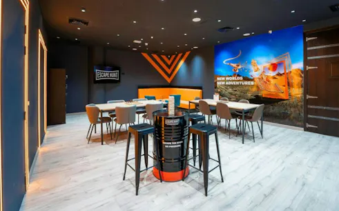 Escape room lobby with tables and chairs, featuring "Escape Hunt" signage and adventure-themed wall art in Dubai.