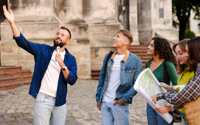 Tour guide with microphone leading tourists near historic building.