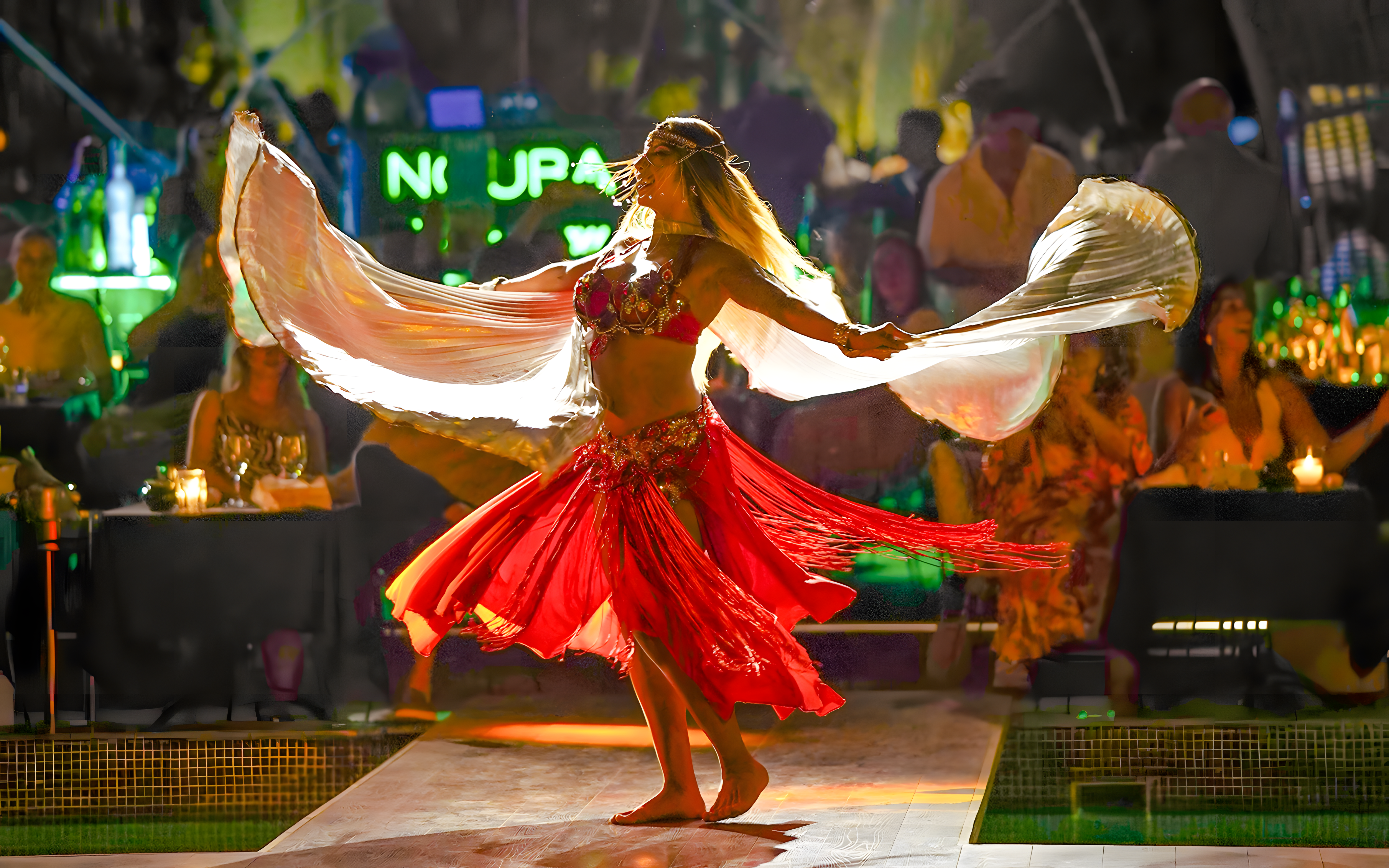 Performer dancing at Nouba Restaurant Dinner Show with vibrant red costume.