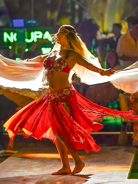 Performer dancing at Nouba Restaurant Dinner Show with vibrant red costume.