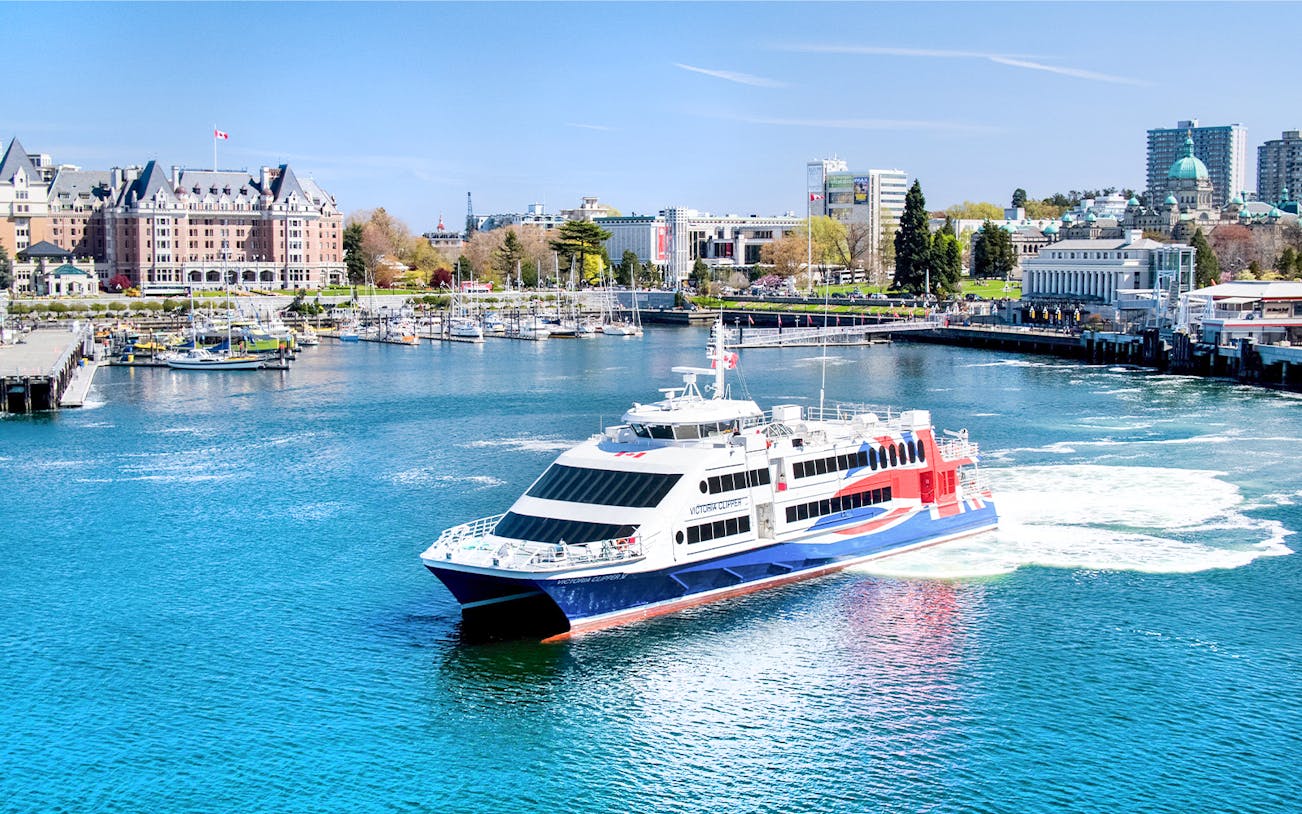 High-speed ferry in Victoria harbor with cityscape and marina views.