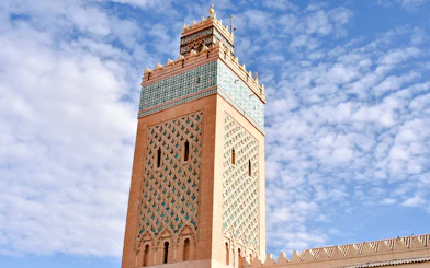 Saadian Tombs Minaret under scattered clouds, Marrakech, Morocco.