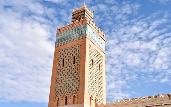 Saadian Tombs Minaret under scattered clouds, Marrakech, Morocco.