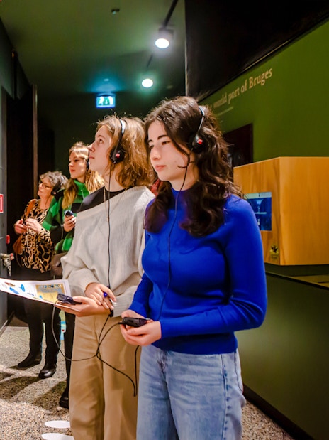 Visitors exploring exhibits with audio guides at Historium Bruges.