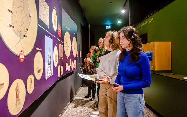 Visitors exploring exhibits with audio guides at Historium Bruges.