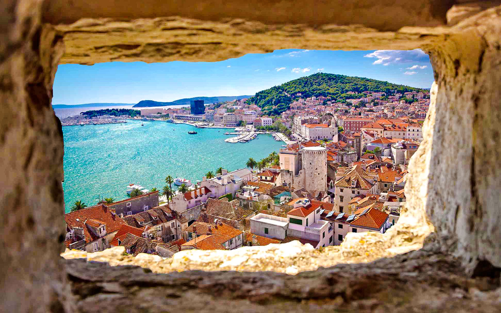View of Split, Croatia from a stone window, featuring the coastline and historic buildings.