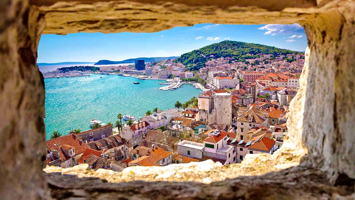 View of Split, Croatia from a stone window, featuring the coastline and historic buildings.