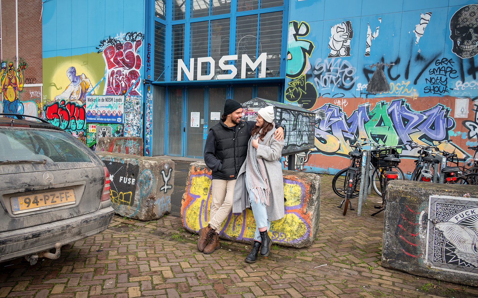 Couple posing in front of graffiti at NDSM, Amsterdam during a professional photoshoot.