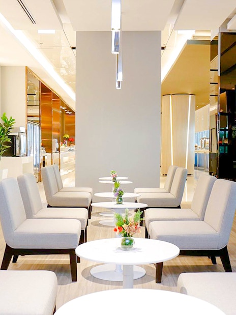 Miracle Lounge seating area with tables and plants, Bangkok airport, Thailand.