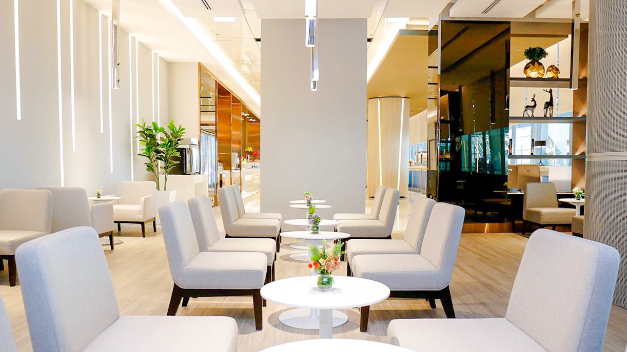 Miracle Lounge seating area with tables and plants, Bangkok airport, Thailand.
