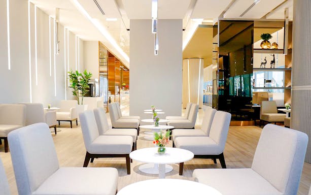 Miracle Lounge seating area with tables and plants, Bangkok airport, Thailand.