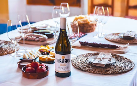 Barcelona wine tour table with Terraprima Blanc bottle, cheese, tomatoes, and wine glasses.