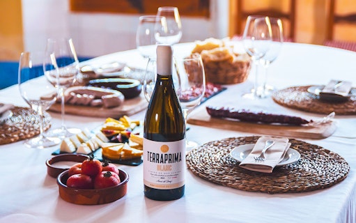 Barcelona wine tour table with Terraprima Blanc bottle, cheese, tomatoes, and wine glasses.