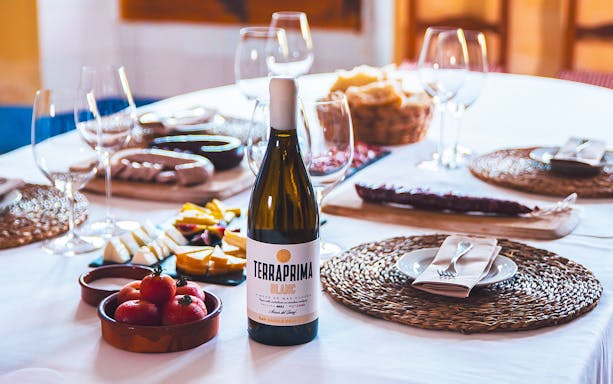 Barcelona wine tour table with Terraprima Blanc bottle, cheese, tomatoes, and wine glasses.