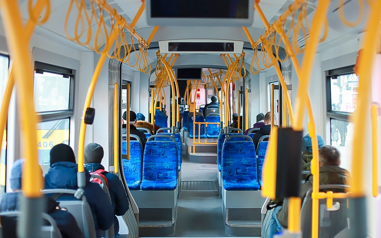 Passengers seated inside Edinburgh Airport transfer bus.