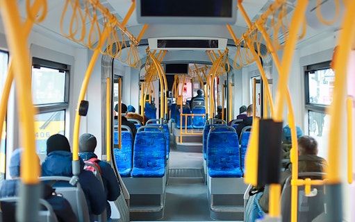 Passengers seated inside Edinburgh Airport transfer bus.