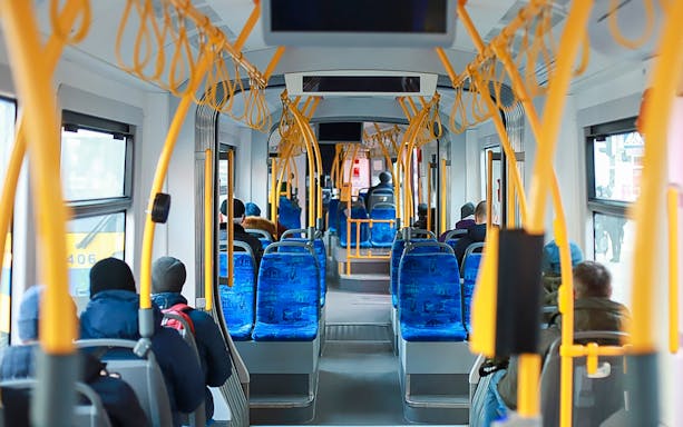 Passengers seated inside Edinburgh Airport transfer bus.