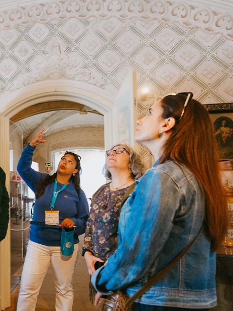 Tour group inside Pena Palace, Sintra, observing ornate ceiling details.