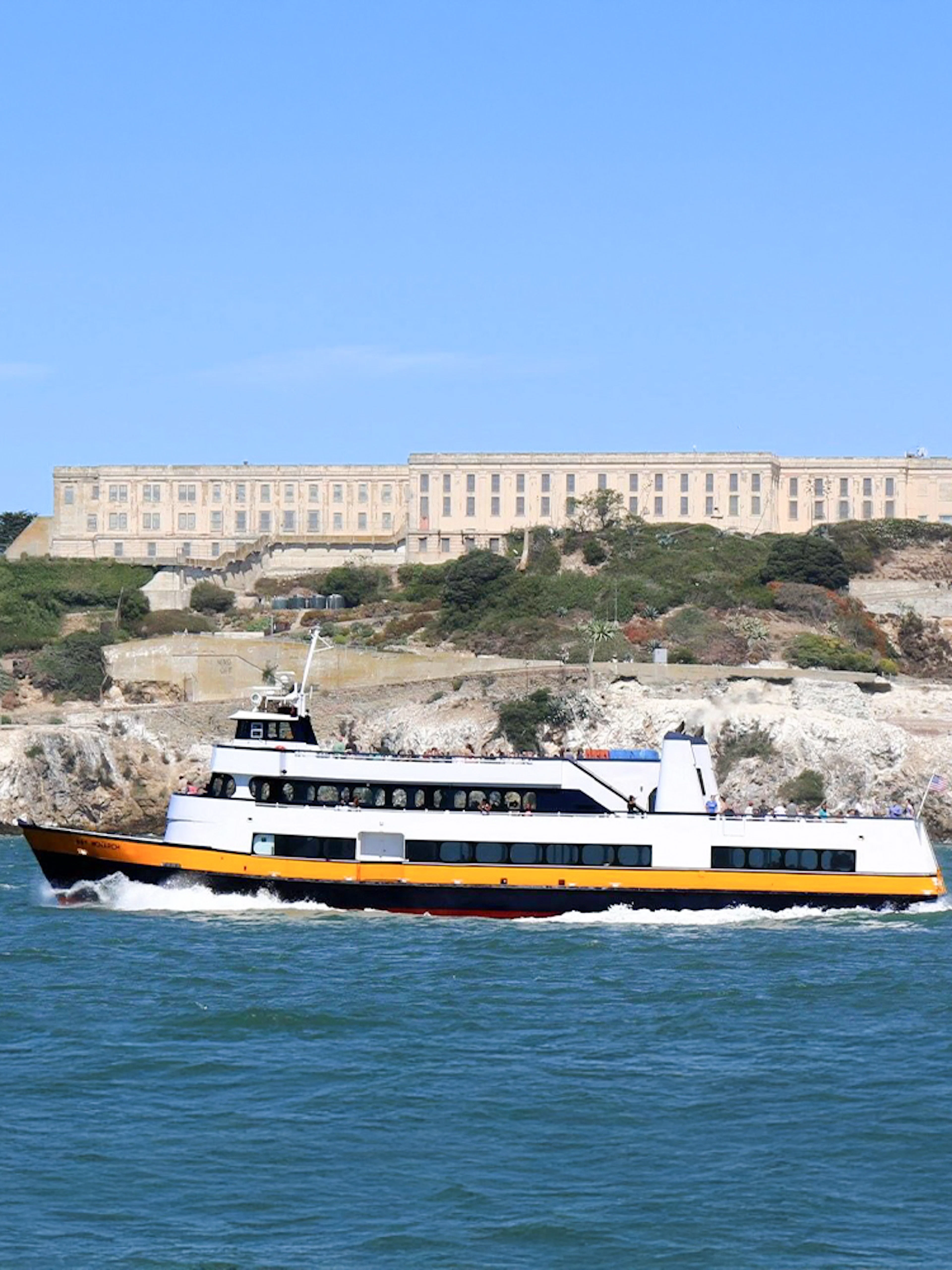 Ferry passing Alcatraz Island with prison buildings in San Francisco Bay, California.