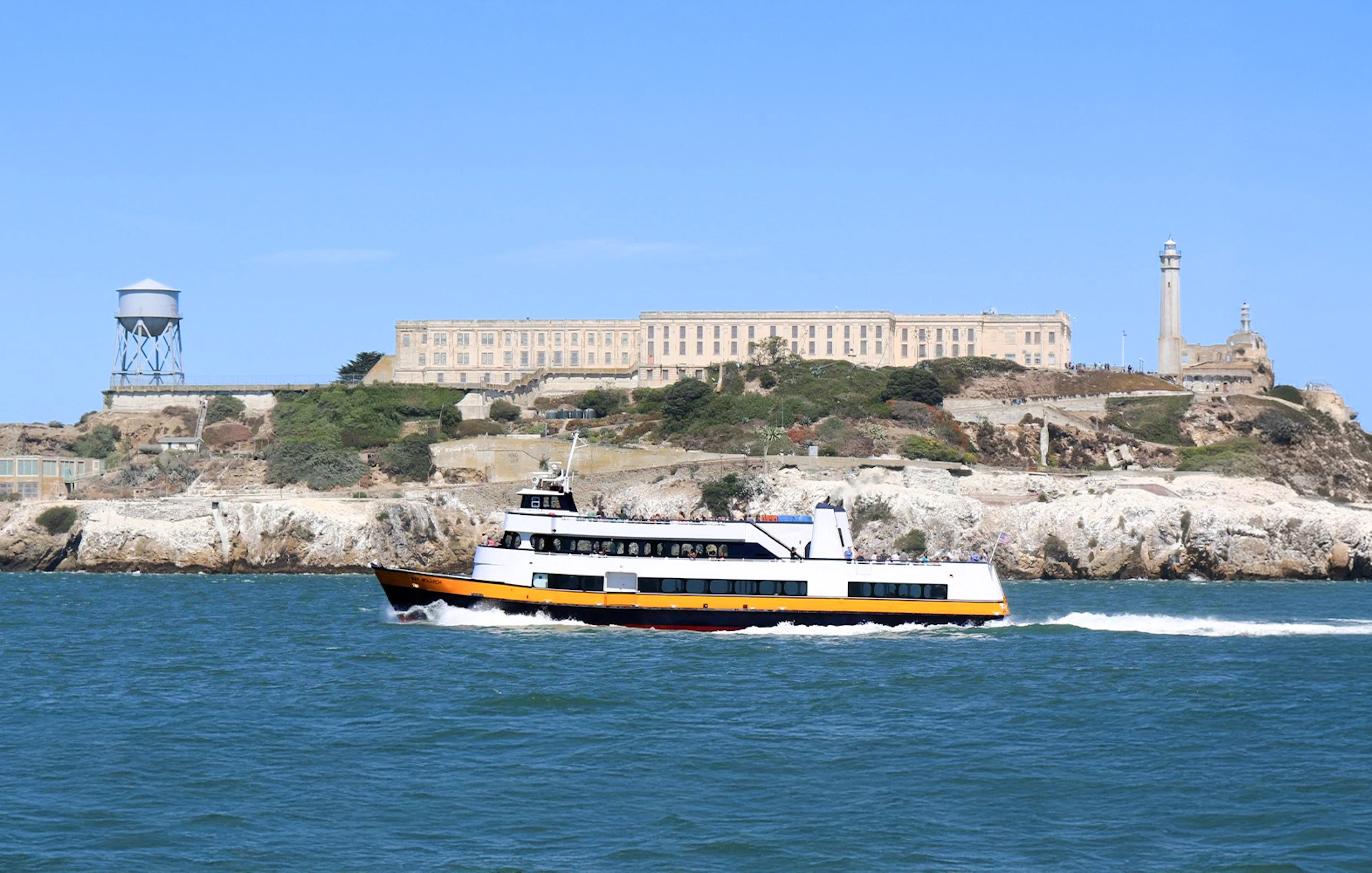 Ferry passing Alcatraz Island with prison buildings in San Francisco Bay, California.