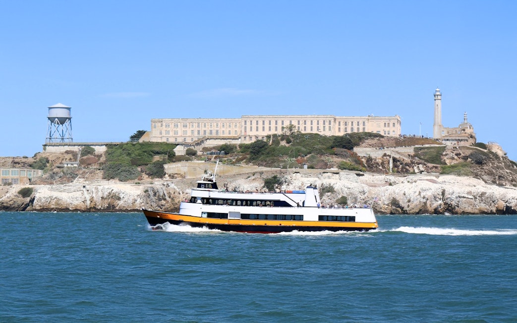 Ferry passing Alcatraz Island with prison buildings in San Francisco Bay, California.