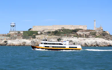 Ferry passing Alcatraz Island with prison buildings in San Francisco Bay, California.