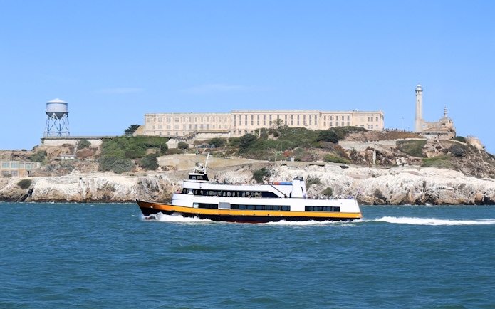 Ferry passing Alcatraz Island with prison buildings in San Francisco Bay, California.