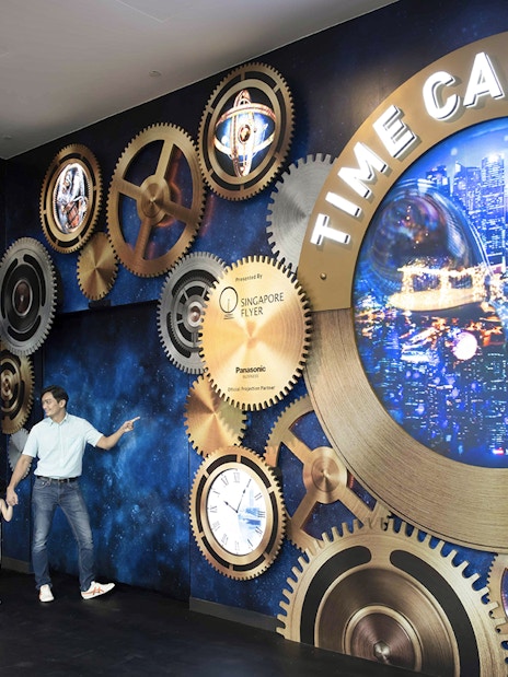 Family exploring Time Capsule exhibit at Singapore Flyer with cityscape display.