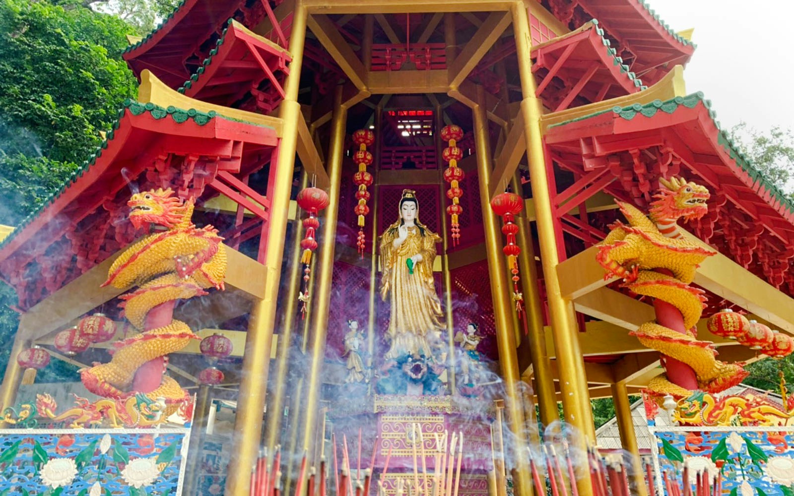 Wat Tham Suea temple shrine with dragon sculptures and incense in Krabi.
