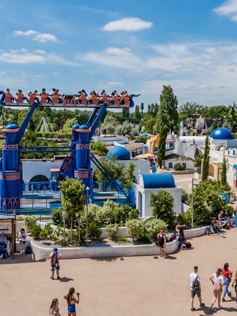 Visitors on a thrilling ride at Astrix Park, Paris, with vibrant attractions and lively atmosphere.
