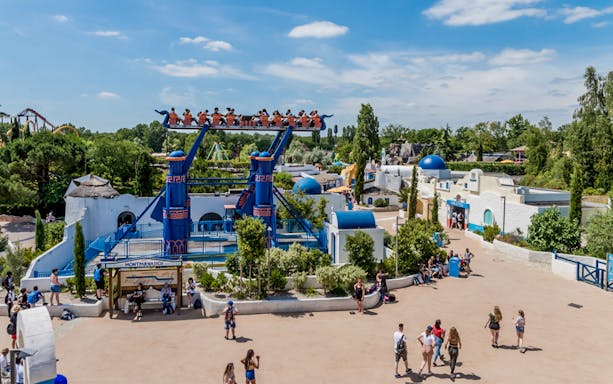 Visitors on a thrilling ride at Astrix Park, Paris, with vibrant attractions and lively atmosphere.
