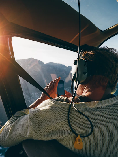 Helicopter passenger photographing mountain landscape at sunrise.