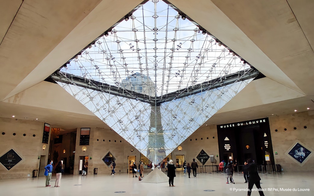 Inverted Pyramid inside Louvre Museum with visitors exploring the area.